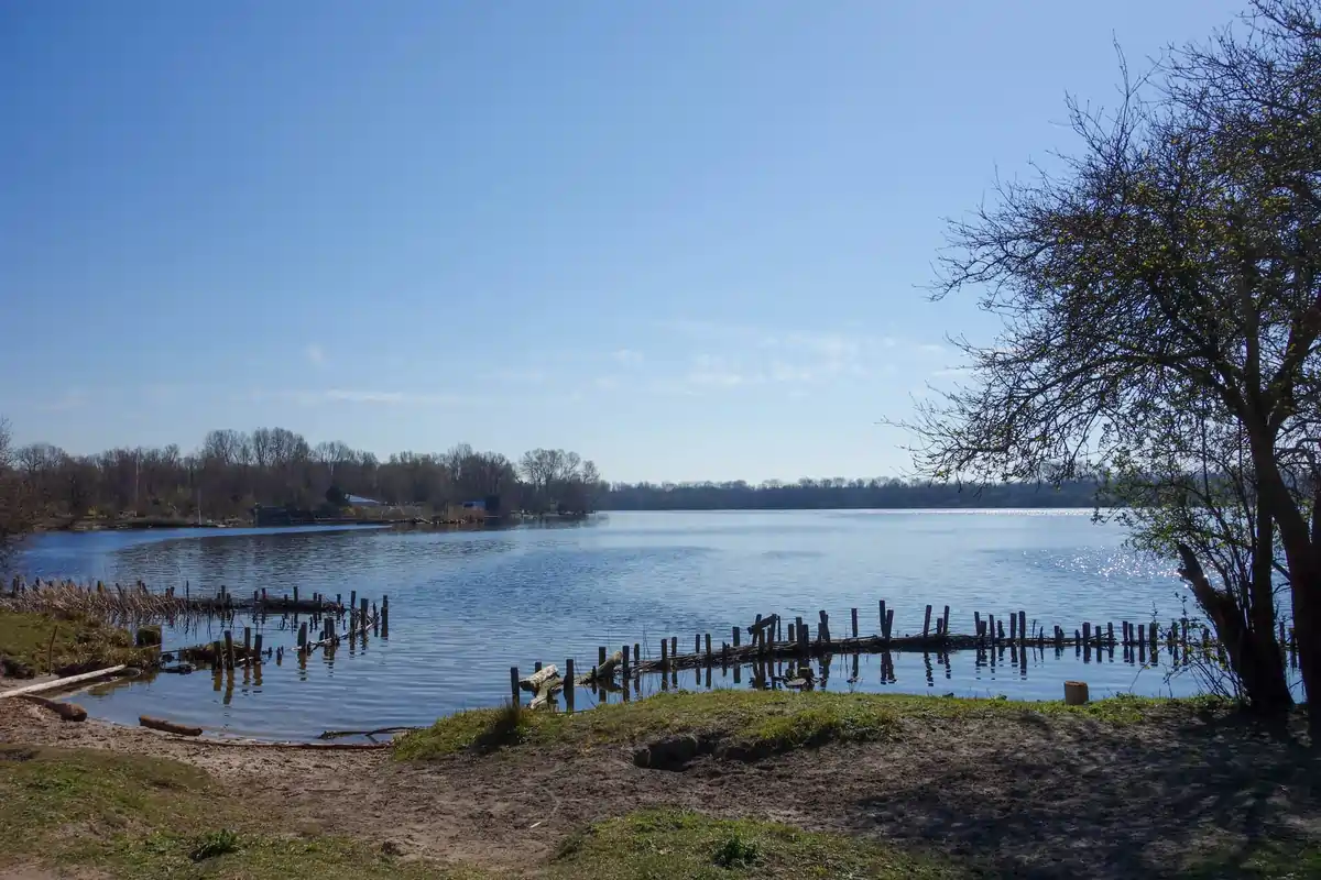 Natural riverside dunes and grassy trails at Park De Oeverlanden, Amsterdam, with Nieuwe Meer Lake in view.