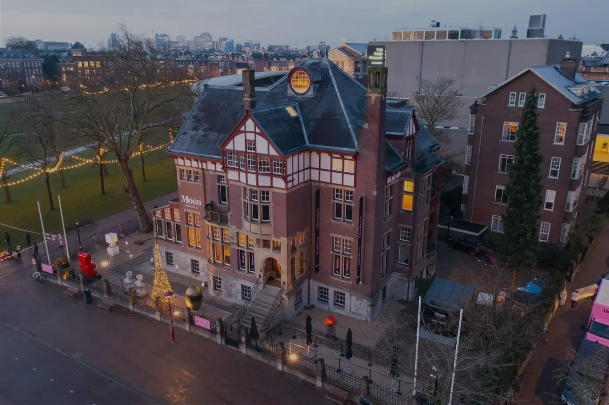 Vibrant exterior of Moco Museum on Museumplein with colorful banners showcasing street and pop art exhibits.