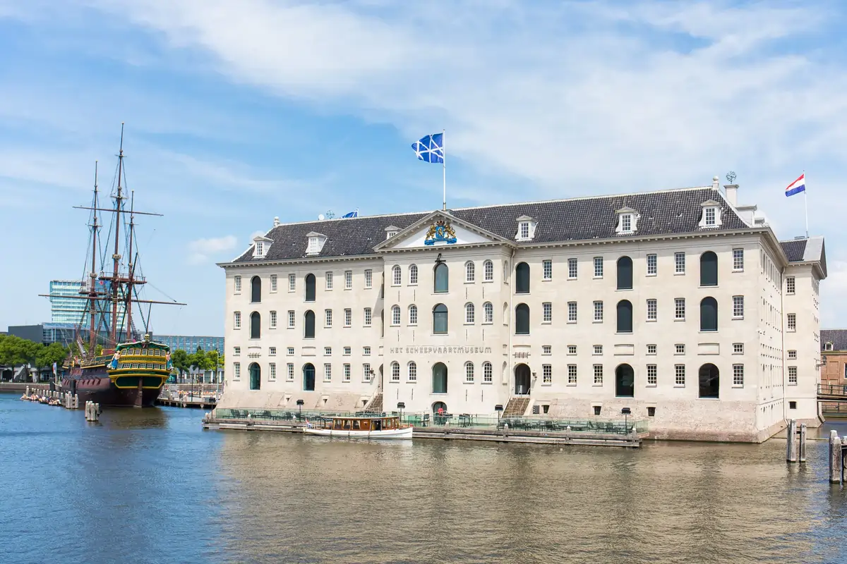 Replica of the 18th-century ship “Amsterdam” docked beside the Scheepvaartmuseum’s grand naval building.