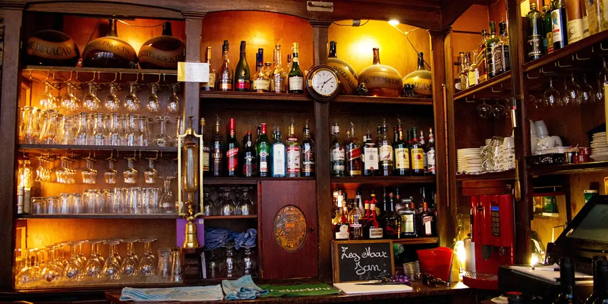 Interior of In ’t Aepjen pub featuring dark wood beams, vintage beer posters, warm lighting