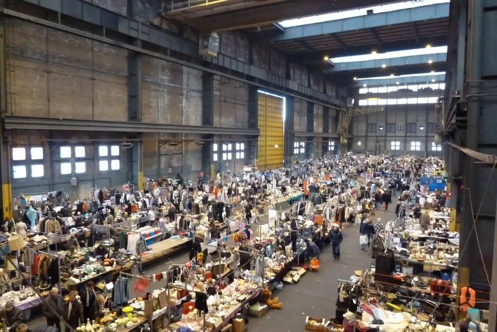 Wide shot of indoor vintage clothing stalls at IJ-Hallen flea market in Amsterdam.